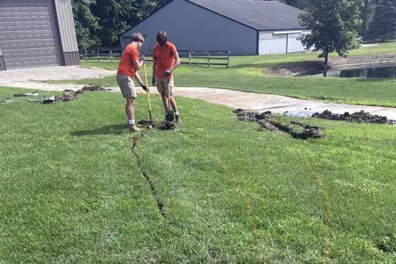 Two technicians running sprinkler waterlines with hose puller for new system Bruce Michhigan